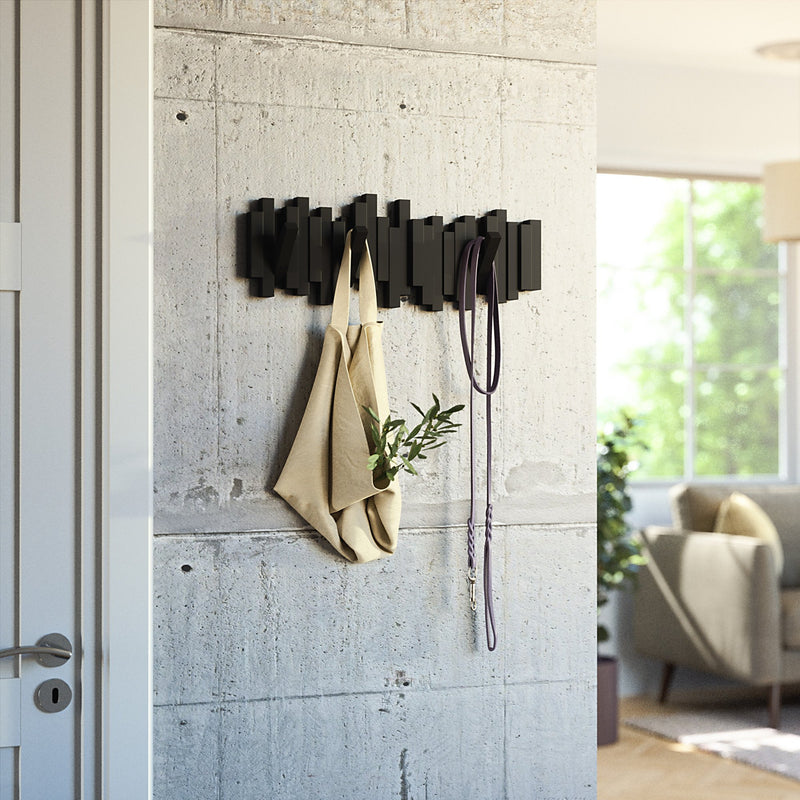 A Umbra Sticks Multi Hook - Black with flip-down hooks hanging in a living room, promoting home organization.