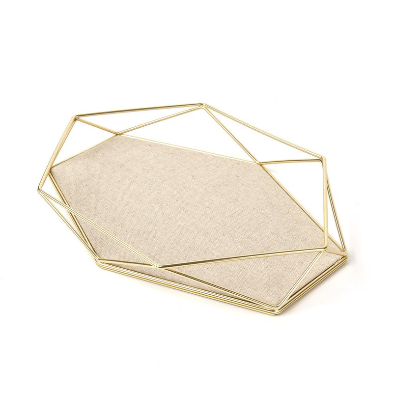 A Prisma Jewellery Tray - Matt Brass from the Umbra range featuring a gold base and topped with a beige fabric.