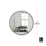 A modern design round mirror from the Umbra range, called the HUB MIRROR GREY 60CM, is shown in front of a living room.