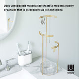 An industrial-inspired bathroom with an Umbra Tesora Jewelry Stand - Glass/ Brass as a striking gold jewelry storage device.