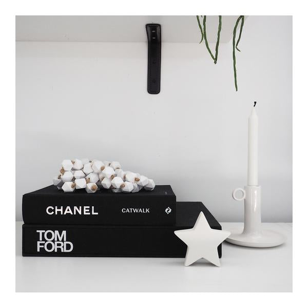 Chanel catwalk: the complete collections books on a shelf with a candle and a star.