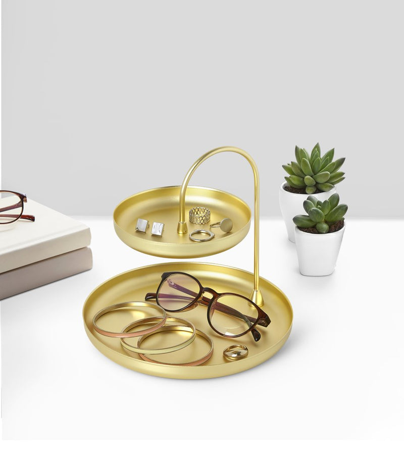 A Poise Two Tier Ring Dish Brass with glasses and a plant on it, perfect as an accessory organizer or jewelry holder. The stylish Poise Two Tier Ring Dish Brass from the Umbra range showcases a sleek design suitable for any contemporary space.