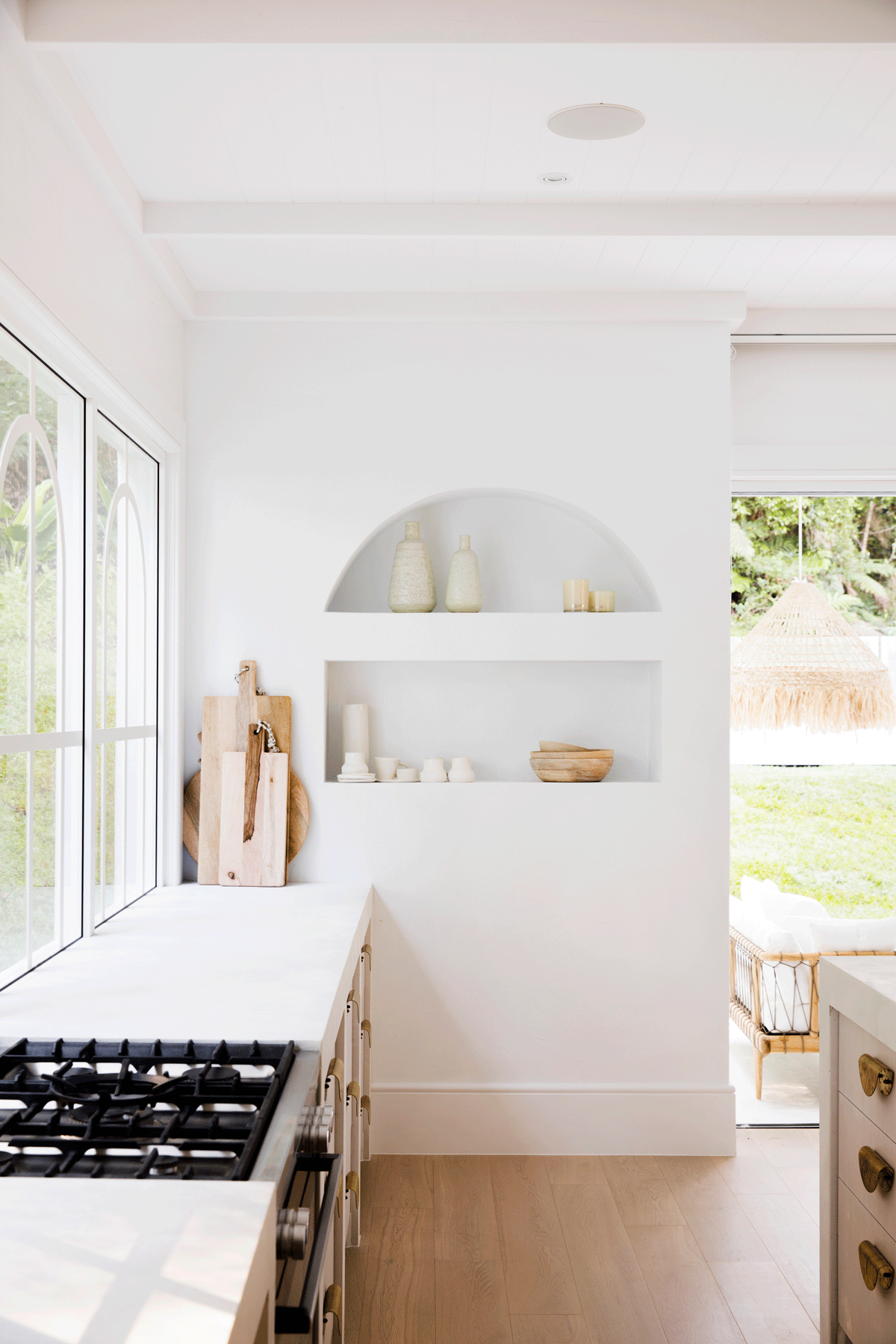 White kitchen with a gas cooktop and arched open shelving