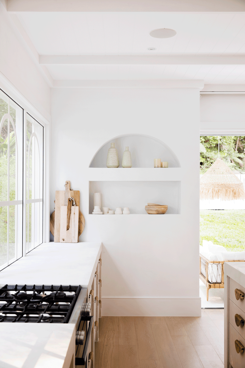 A white kitchen with wooden cabinets and a window, showcasing the Three Birds Renovations: Dream Home How-To book goodness and home transformations.