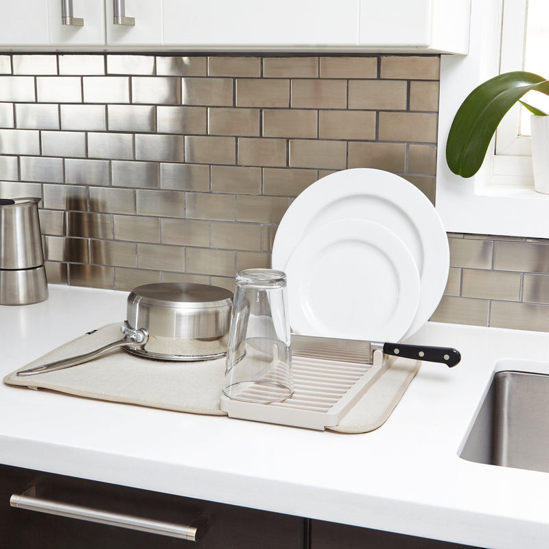 An Umbra kitchen counter with a sink and a Udry Drying Mat Mini compact storage.