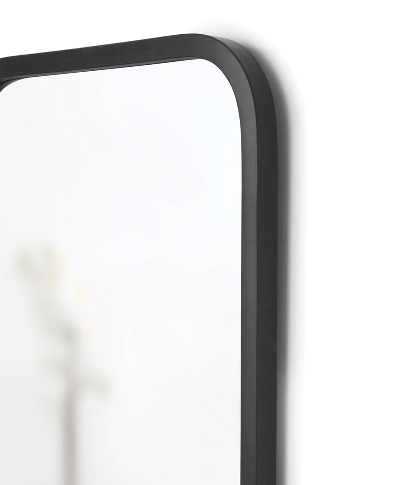 An Umbra Hub Mirror - Rectangle 61X91" Black with a black frame on a white wall.