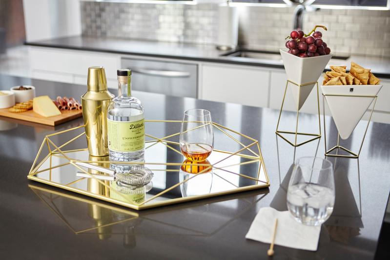 A Prisma Mirror - Brass, part of the Umbra range, sits on a kitchen counter next to a bottle of wine.