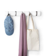 An Umbra Flip 5 Hook White coat rack with retractable hooks providing space-saving functionality for hanging a hat, bag, and tote.