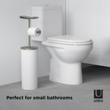 In a bathroom, an Umbra Portaloo Toilet Paper Stand - White/Nickel is placed next to a toilet.