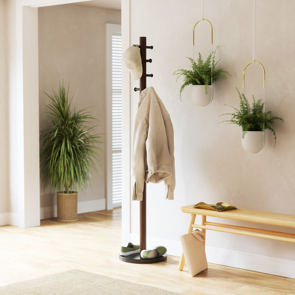 An Umbra Pillar Coat Rack in a room with plants and a bench, providing storage and order.